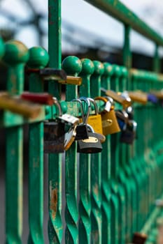 A lot of old padlocks hanging on old green fence