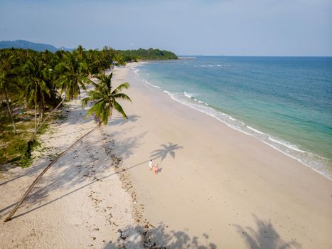 couple on vacation in Thailand, Chumpon province, white tropical beach with palm trees, Wua Laen beach Chumphon area Thailand, palm tree hanging over the beach with a couple on vacation in Thailand.