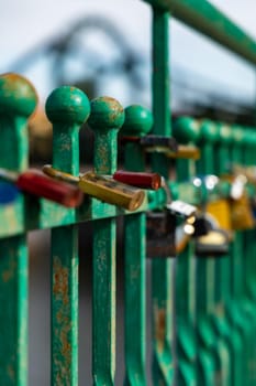 A lot of old padlocks hanging on old green fence