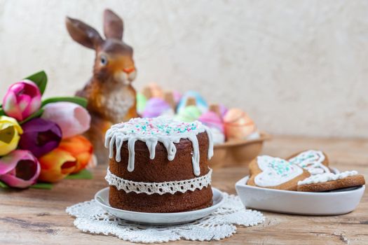 Easter still life with cake, homemade cookies, decorative figurine of rabbit and Easter eggs on a wooden table. The concept of celebrating the Christian holiday of Easter.