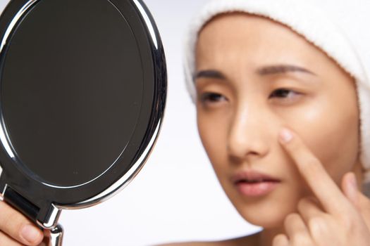 Asian woman looking at the mirror and touching with my hand face clean skin health cosmetology. High quality photo