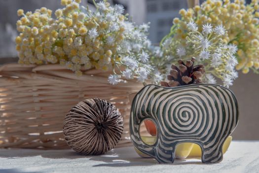 Set of Elephants shaped ceramics cup with Dried cerbera oddloam's seed and Bouquet of flowers in woven basket to Decorate the house beautifully. Elephants shaped cup for dipping sauce, Selective focus.