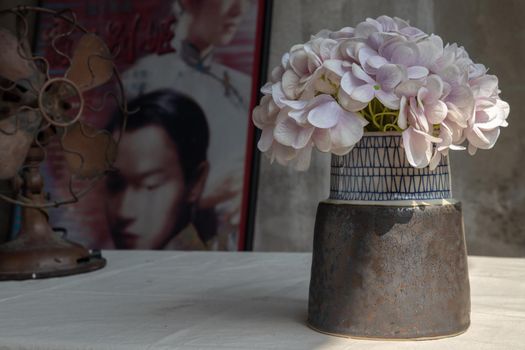 Bouquet of flowers in Handmade ceramic vase on white textured table cloth in Chinese retro style room with old ruins cement wall. Home decor, Space for text, Selective focus.