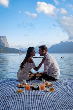 couple having breakfast in front of wooden floating room visiting Khao Sok national park in Phangnga Thailand, Khao Sok National Park, Cheow Lan lake, Ratchaphapha dam. man and woman mid age vacation 