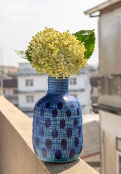 A bouquet of flowers in a blue ceramic vase on old cement wall at the balcony house. Home decor, select focus.