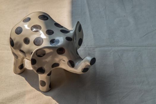 Elephants shaped ceramic on white textured table cloth. Home decor, Copy space, No focus, specifically.
