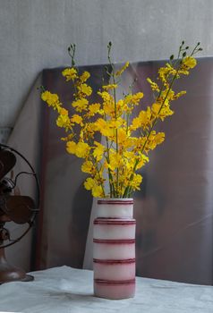 Bouquet of yellow flowers in Pink handmade ceramic vase and Vintage fan on white textured table cloth with old cement wall. Home decor, Selective focus.