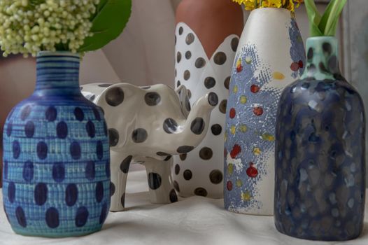 Bangkok, Thailand - Feb 06, 2021: Elephant shaped ceramic and Handmade Assorted Many Different Ceramic Polka Dotted Vases on white textured table cloth. Home decor, Space for text, Selective focus.