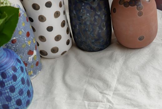 Details of Handmade Assorted Many Different Ceramic Polka Dotted Vases on white textured table cloth. Home decor, Space for text, Selective focus.