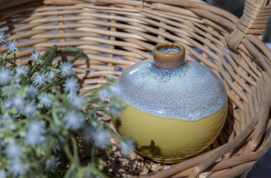 Small  yellow ceramic vases with bouquet of flowers in woven basket. Home decor, Selective focus.