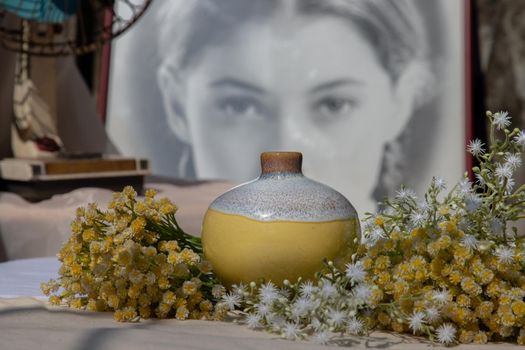 Bangkok, Thailand - Feb 06, 2021: Small yellow ceramic vases with old vintage fan on pink textured table cloth in front of Chinese poster movie frame. Home decor, Selective focus.