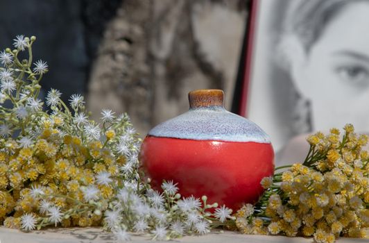 Bangkok, Thailand - Feb 06, 2021: Small red ceramic vases on pink textured table cloth in front of Chinese poster movie frame. Home decor, Selective focus.