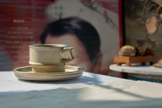 Ceramic mug handmade in Chinese retro style room with old ruins cement wall. Selective focus.