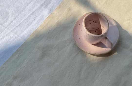 Beautiful pink ceramic mug on white textured table cloth. Space for text, Top view, Selective focus.