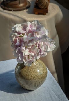 Bouquet of purple flowers in Handmade ceramic vaseon white textured table cloth. Home decor, Selective focus.