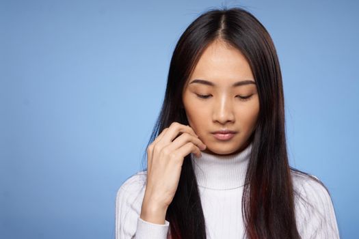 brunette asian touching face with hand makeup model white sweater. High quality photo