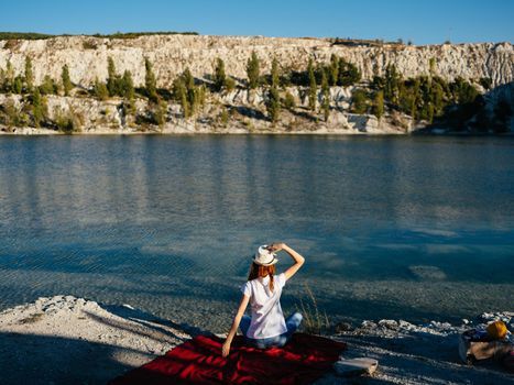 Happy woman resting in nature near the river and red cloth on the bank. High quality photo