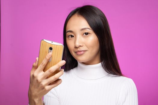 cute asian appearance phone in hand internet communication technology pink background. High quality photo