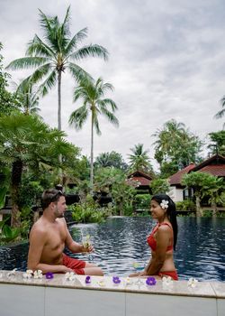 men and woman mid age in swimming pool in Asia, couple European man and Asian woman on vacation relaxing by pool