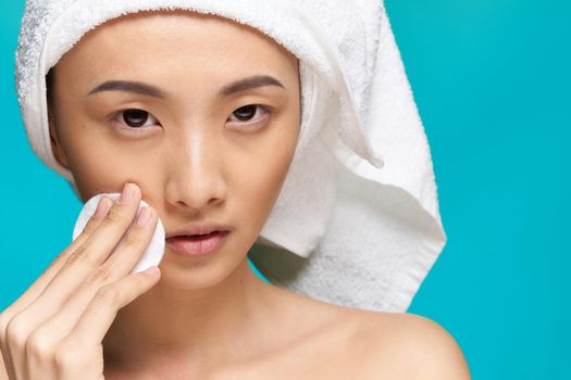 pretty woman towel on head wiping face with cotton pad health blue background. High quality photo
