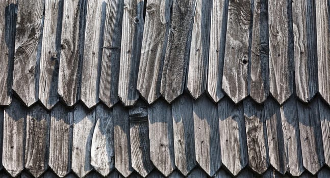 Fragment of the wall of an old rural house made of wooden planks. Background texture of old wooden wall. 