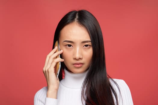 woman of asian appearance talking on the phone technology emotions red background. High quality photo