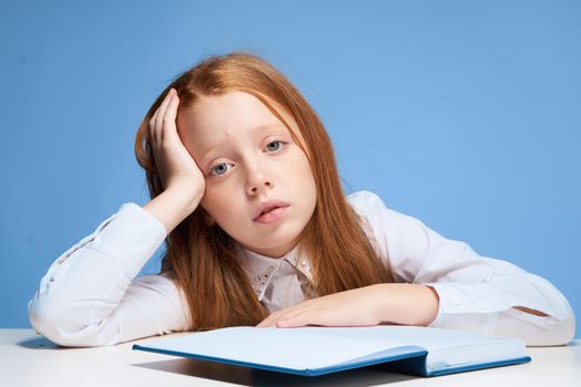 schoolgirl turned pretend sitting at the table and doing learning lessons. High quality photo