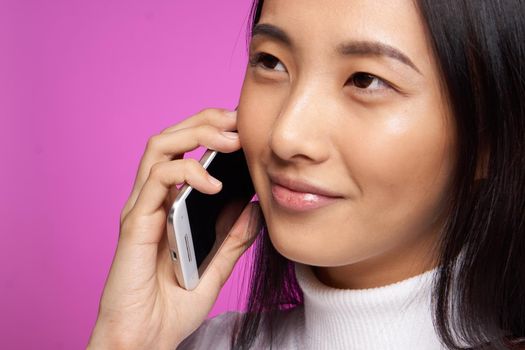 asian woman talking on the phone cropped view pink background. High quality photo