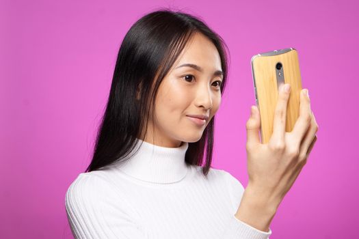 pretty woman in white sweater phone in hands pink background fashion communication. High quality photo
