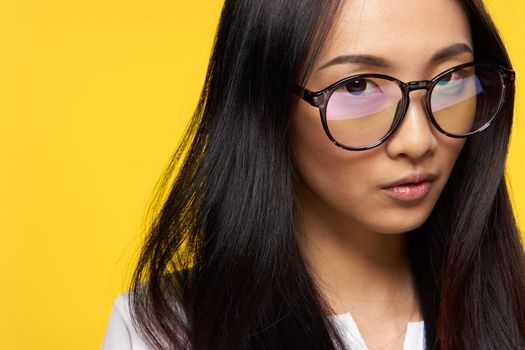 attractive woman asian appearance glasses close-up yellow background glamor. High quality photo