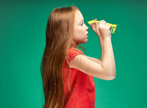cheerful girl with red hair and a red t-shirt yellow glasses emotions studio. High quality photo