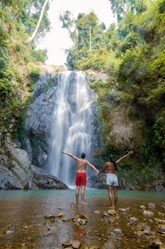 couple of men and women mid-age visiting a waterfall in Thailand, A tourist is enjoying the beauty of the waterfall in Chumphon province, Thailand, Klongphrao waterfall Thailand. Asia