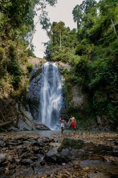 couple of men and women mid-age visiting a waterfall in Thailand, A tourist is enjoying the beauty of the waterfall in Chumphon province, Thailand, Klongphrao waterfall Thailand. Asia