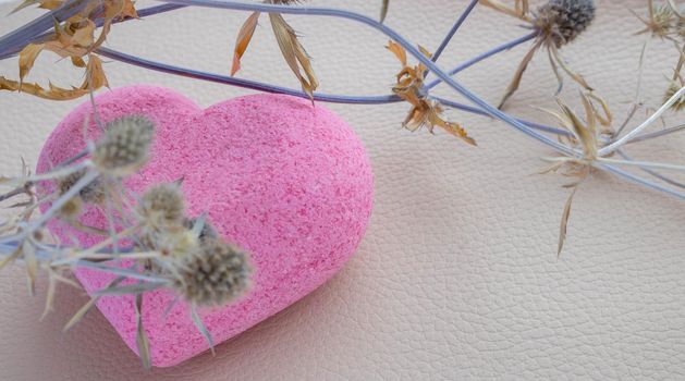 Purple heart bath salt and a dry branch on a beige background. Space for text.