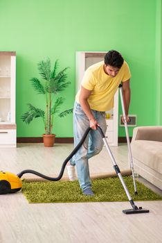 Injured man on crutches vacuum cleaning house