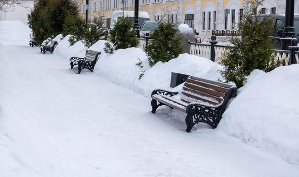 Winter landscape.Snow-covered benches in the alley.