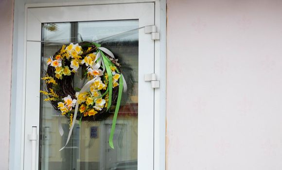 Photo of a seasonal spring wreath with daffodils on a glass door.