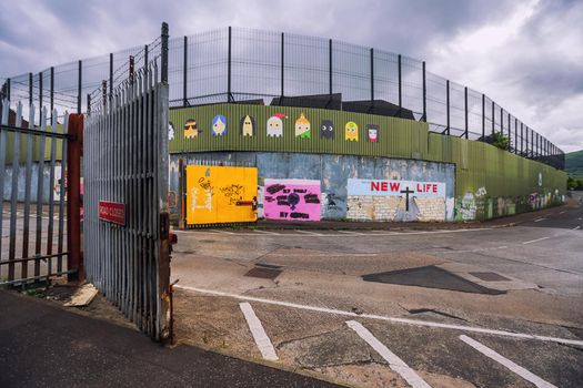 Belfast, Northern Ireland, UK - June 26, 2017: Open metal gate close to Peace Wall on crossroad of North Howard Street and Cupar Way that separate catholics and protestants.