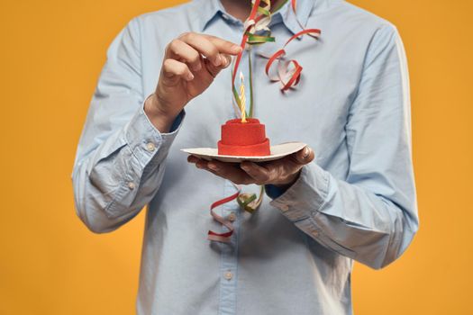 A man holding a cake in a plate and a candle from above isolated background. High quality photo