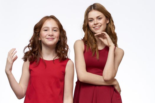 Cheerful mom and daughter next to red dresses hugs lifestyle light background smile. High quality photo