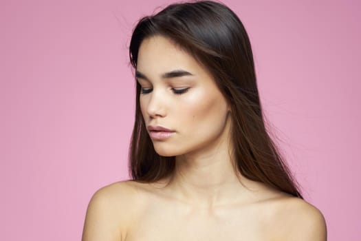 brunette bare shoulders clear skin body care pink background. High quality photo