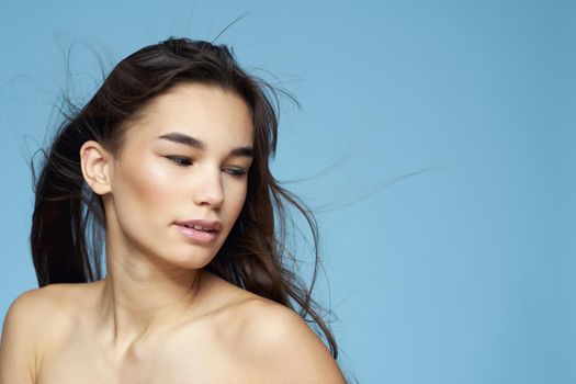 Woman with naked shoulders long hair cosmetics attractive look blue background. High quality photo