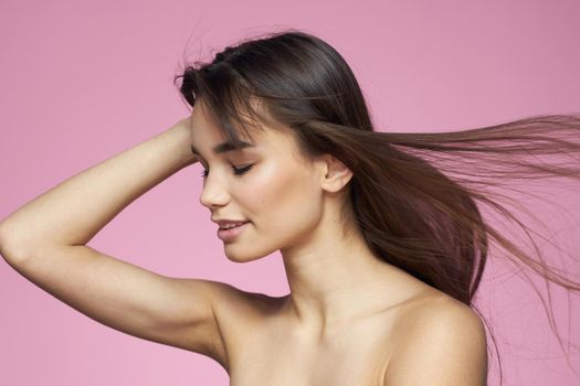 Pretty brunette naked shoulders clear skin pink background. High quality photo