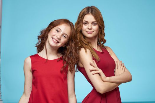 Family mom and daughter hug red dresses communication emotions blue background. High quality photo