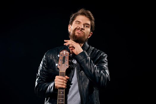 A man with a guitar in his hands leather jacket music performance rock star modern style dark background. High quality photo