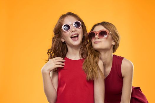 cheerful mom and daughter wearing sunglasses lifestyle friendship family yellow background studio. High quality photo