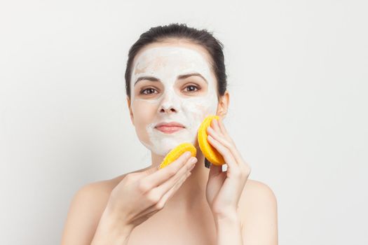 joyful woman with bare shoulders cream mask on face scrub sponges in hands. High quality photo