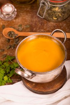 Bowl of pumpkin soup on rustic wooden background.
