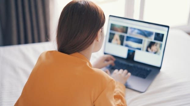 woman in bedroom lies on bed in front of laptop communication technology. High quality photo