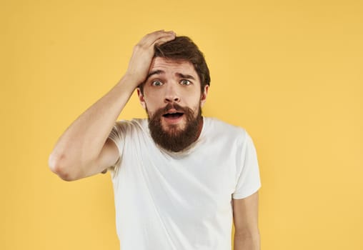 Upset man holds his hands near his face on a yellow background. High quality photo